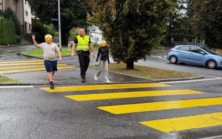 Mitarbeiter von AC Security im Verkehrsdienst bei der Schulwegsicherung an einem Fussgängerstreifen, Gesichter der Kinder unkenntlich gemacht